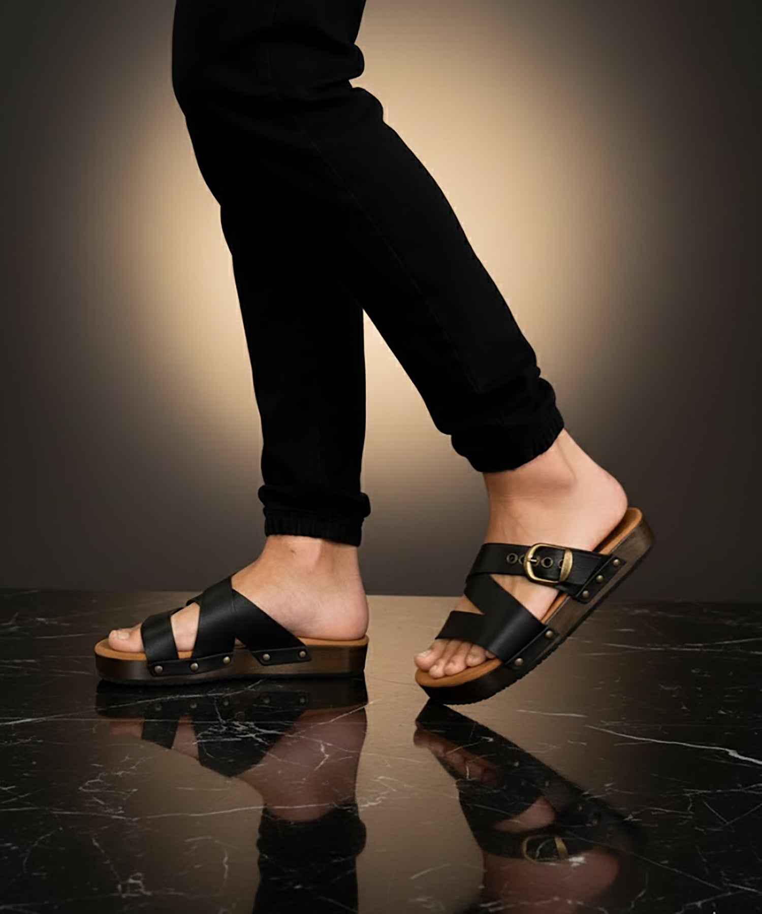 Man wearing handmade black leather wooden sole sandals outdoors, showing fit and rugged style.