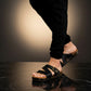 Man wearing handmade black leather wooden sole sandals outdoors, showing fit and rugged style.