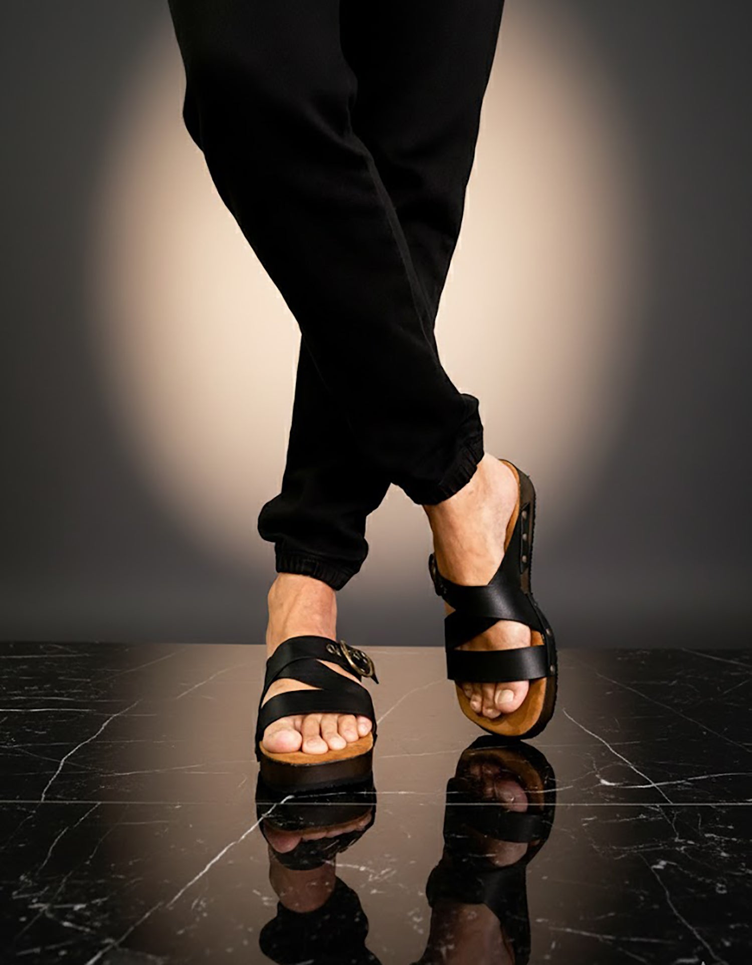 Man wearing handmade black leather wooden sole sandals outdoors, showing fit and rugged style.