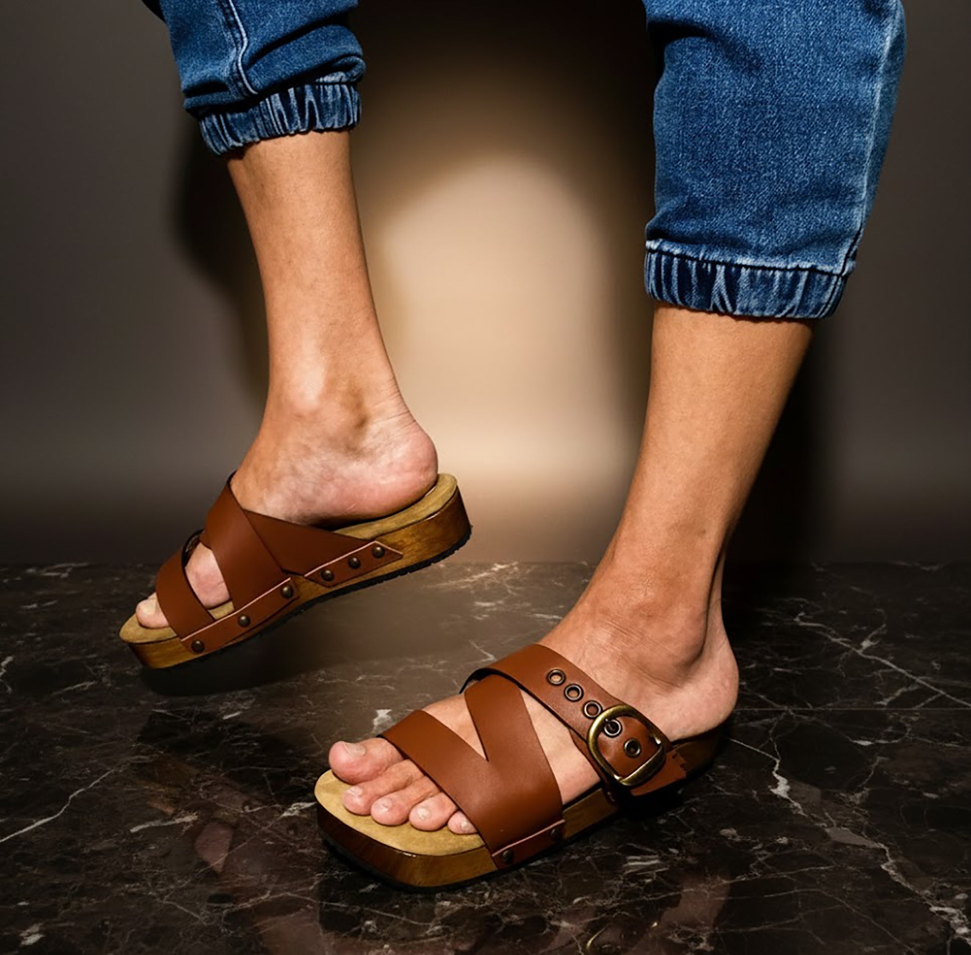 Man wearing handmade brown leather wooden sole sandals outdoors, showing fit and rugged style.