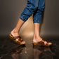Man wearing handmade brown leather wooden sole sandals outdoors, showing fit and rugged style.