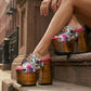 Close-up image of a model from the waist down wearing the Luxury Queen Tattoo Sandals by Sol Caleyo and rolled-up dark denim jeans, posing on a classic brownstone stone staircase in New York City.