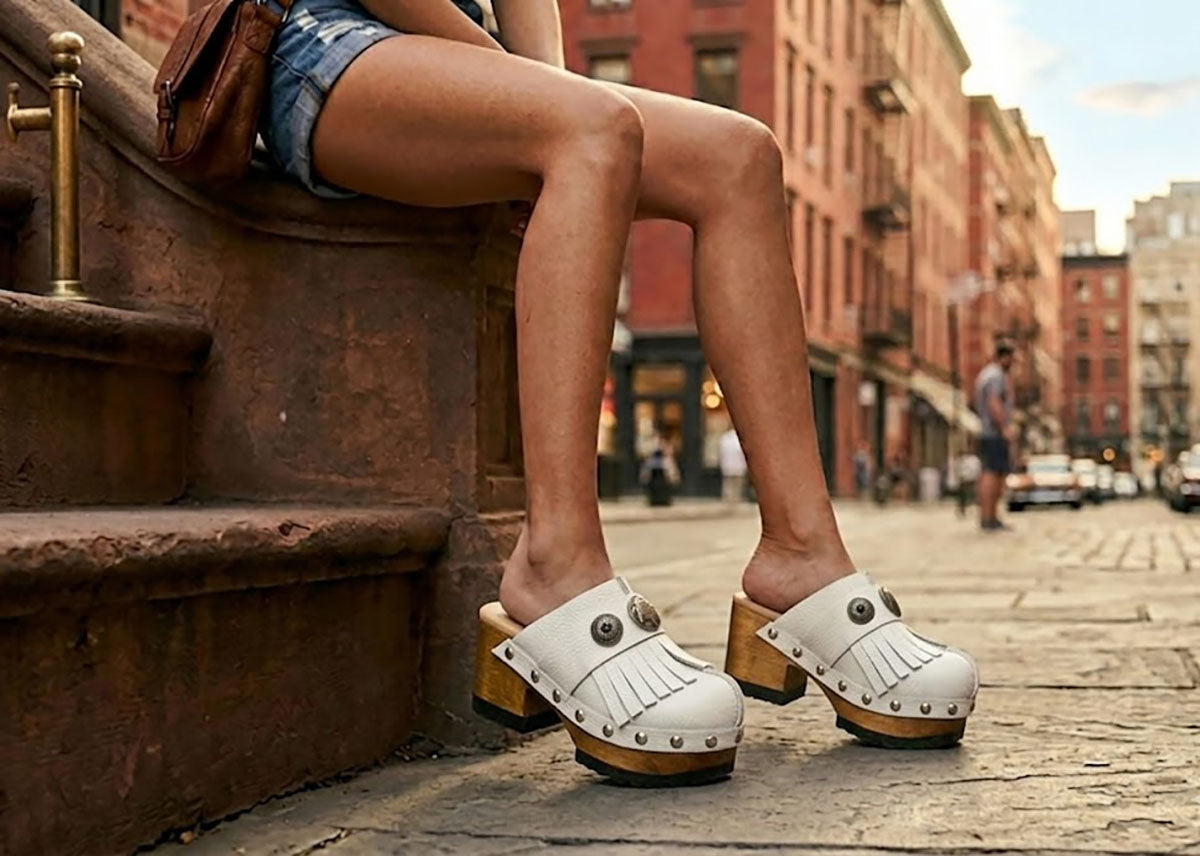 Model wearing Sol Caleyo White Indian Clogs featuring leather fringes and shells, styled for a high-end bohemian summer look.