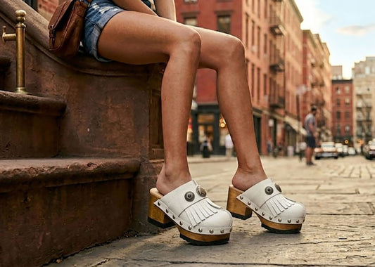 Model wearing Sol Caleyo White Indian Clogs featuring leather fringes and shells, styled for a high-end bohemian summer look.