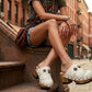Model wearing Sol Caleyo White Indian Clogs featuring leather fringes and shells, styled for a high-end bohemian summer look.