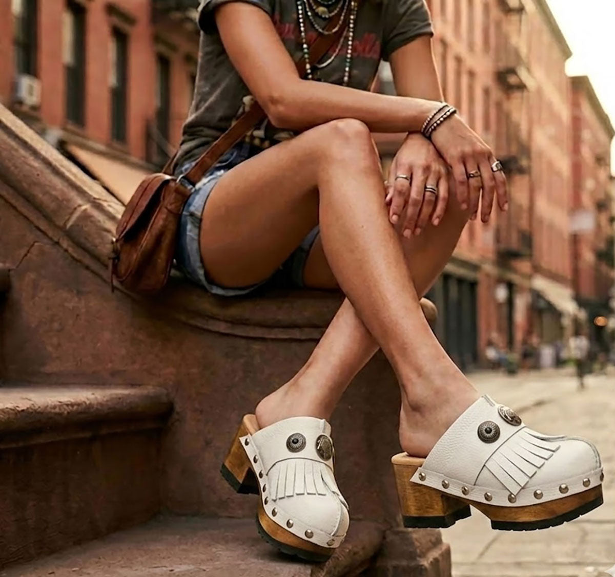 Model wearing Sol Caleyo White Indian Clogs featuring leather fringes and shells, styled for a high-end bohemian summer look.