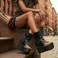 Model wearing Sol Caleyo Texas artisan sandals. High-end platform footwear in black leather with silver hardware and studded details. Luxury handmade wooden wedge sandals for a bold bohemian look.