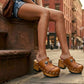 A woman sitting on New York brownstone steps wearing Sol Caleyo bohemian leather platform clogs and denim shorts.