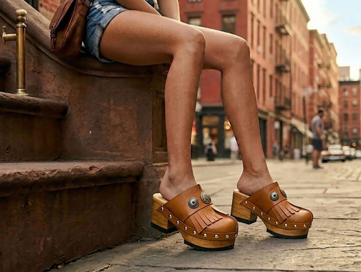 A woman sitting on New York brownstone steps wearing Sol Caleyo bohemian leather platform clogs and denim shorts.