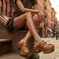 A woman sitting on New York brownstone steps wearing Sol Caleyo bohemian leather platform clogs and denim shorts.
