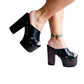 Handmade smooth black leather open toe platform mule sandals with two crossed straps, round flat old-gold studs and 15 cm straight wenge lacquered wooden heel by Sol Caleyo.