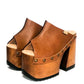 Handmade full-grain camel leather open toe mule clogs with old-gold studs and 14 cm natural lacquered bell-shaped wooden heel by Sol Caleyo.