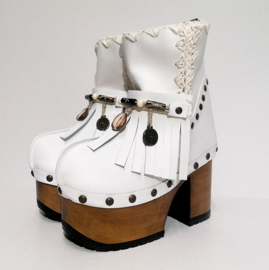 White leather clog boot. White leather boho style clog boot. White leather boot decorated with fringes, shells, coins and carved bone with a unique boho style. Super high heeled wooden boots 70's style. Sizes 34 to 47. High quality handmade leather shoes by sol Caleyo. Sustainable fashion.