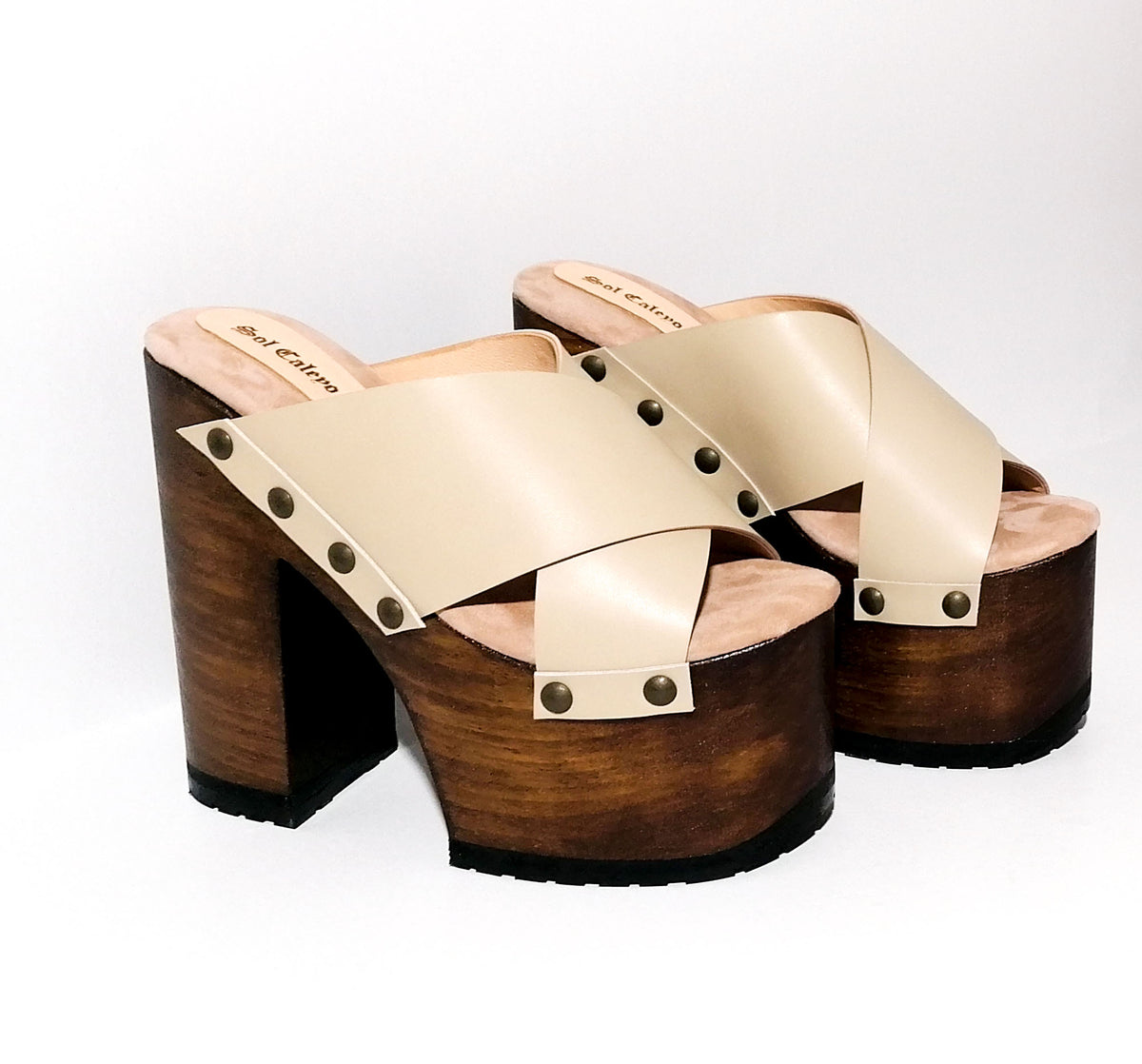 Handmade smooth nude leather open toe platform mule sandals with two wide crossed straps, round flat old-gold studs and 15 cm straight dark oak lacquered wooden heel by Sol Caleyo.