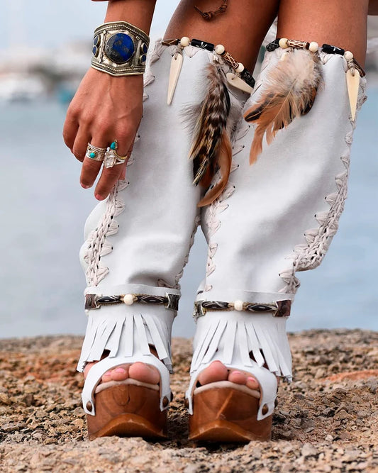 Handmade white split suede open toe slouch wedge boots with fringe, natural feathers, horns, brown resin figure and python print heel on a 6 cm natural lacquered wooden wedge by Sol Caleyo.
