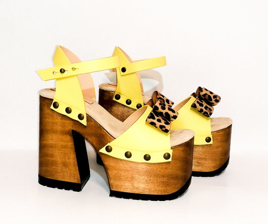 Handmade yellow leather bell heel platform sandals with animal print leather bow, ankle strap, old-gold studs and 14 cm natural lacquered wooden heel by Sol Caleyo.