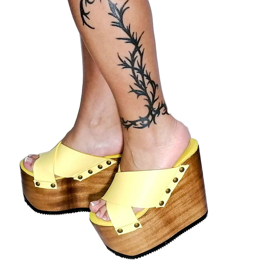 Handmade smooth bright yellow leather wedge sandals with round flat old-gold studs and 15 cm natural lacquered wooden wedge by Sol Caleyo.